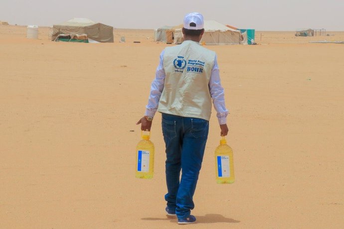 Archivo - Un trabajador lleva botellas de aceite vegetal del PMA para distribuirlas entre los desplazados internos en un campamento de Yemen