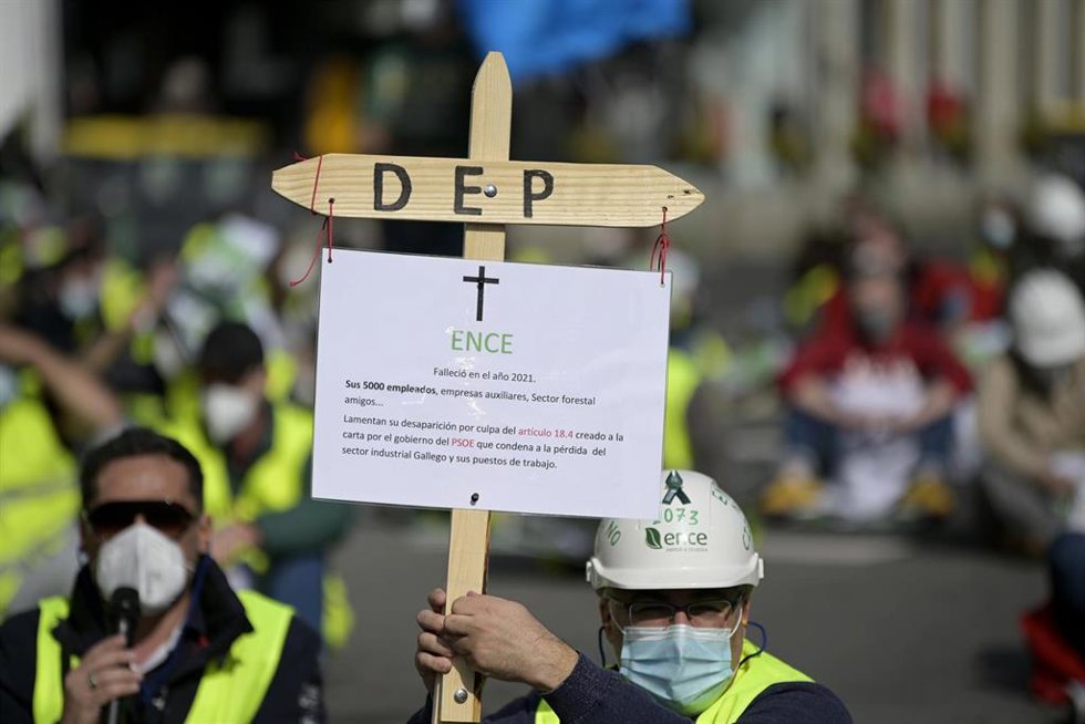 Archivo - Un trabajador de ENCE Pontevedra sostiene una esquela que simula su puesto de trabajo acompañado por transportistas de madera durante una sentada organizada en A Coruña delante de la Delegación del Gobierno