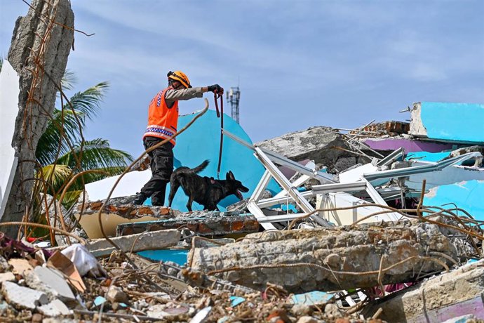 Archivo - Un miembro de la unidad K-9 de la policía conduce un perro rastreador mientras buscan víctimas entre los escombros de un edificio derrumbado tras el terremoto ocurrido en Mamuju, regencia de la provincia indonesia de Sulawesi Occidental