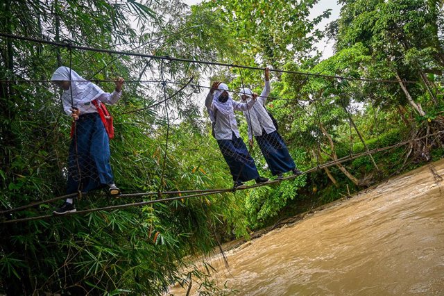 Archivo - 13 September 2021, Indonesia, Luwu: Children cross a river using a badly damaged bridge to go to his school in Malela. The bridge that has been damaged by the flood is still being used by residents to cut travel time to other villages. Photo: Ha