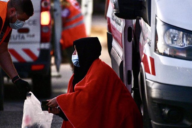 Archivo - Una migrante es atendida por un voluntario de Cruz Roja