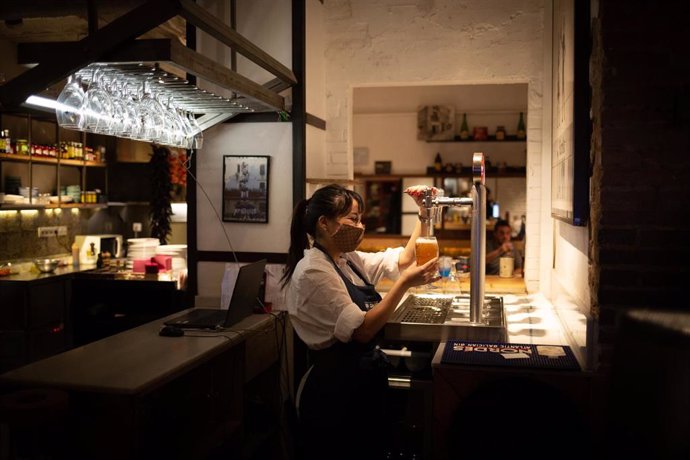 Una camarera sirve una cerveza en el interior de un bar en una calle céntrica de Barcelona, a 14 de octubre de 2021, en Barcelona, Catalunya (España). A partir de este viernes en Cataluña se terminarán las limitaciones de aforo en los equipamientos cult