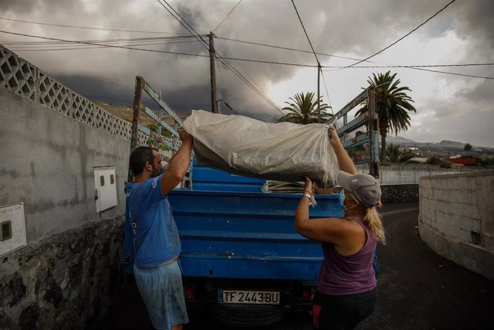 Un hombre y una mujer sacan sus pertenencias de su casa por la actividad del volcán de Cumbre Vieja