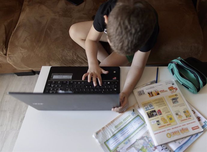 Archivo - Un alumno de Primaria haciendo los deberes de la asignatura de Inglés con varios libros y un ordenador durante el confinamiento