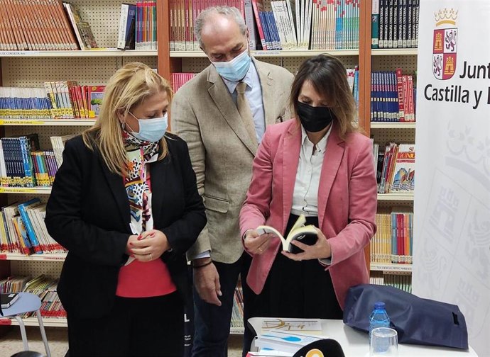 La consejera de Educación, Rocío Lucas, (d) consulta un libro en la presentación en Soria de un Plan de Lectura.