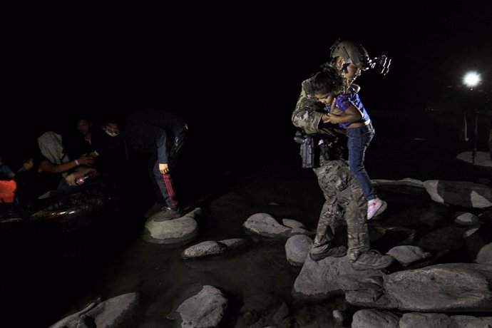 Archivo - 05 May 2021, US, La Joya: A soldier carries away a migrant child after a group of asylum seekers crossed the Rio Grande River at the Texan borders with Mexico. Photo: Carol Guzy/ZUMA Wire/dpa