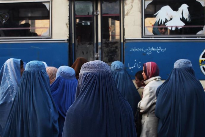 Un grupo de mujeres afganas espera para abordar un autobús