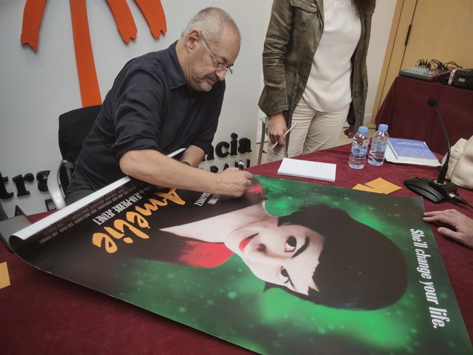 El director Jean-Pierre Jeunet firma un cartel de 'Amélie' durante la rueda de prensa con motivo de la Parmera de Honor que le ha otorgado la Mostra de Valncia- Cinema del Mediterrani