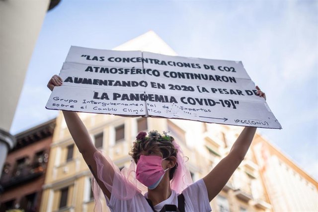 Una mujer con un cartel en el que se lee: 'Las concentraciones de CO2 atmosférico continuaron aumentando en 2020', participa en una protesta contra el Gobierno por la inacción climática, en la calle Atocha, a 18 de octubre de 2021, en Madrid (España). Dur