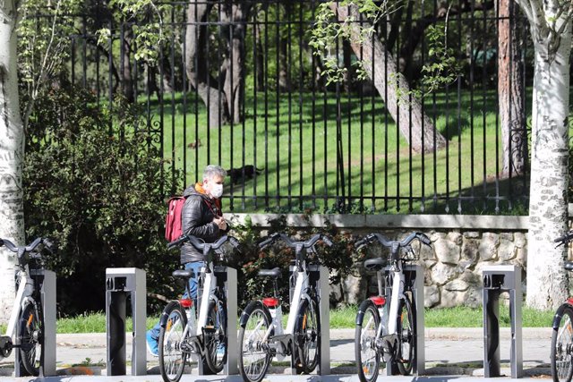 Archivo - Un hombre pasa junto a bicicletas de BiciMAD en una estación .