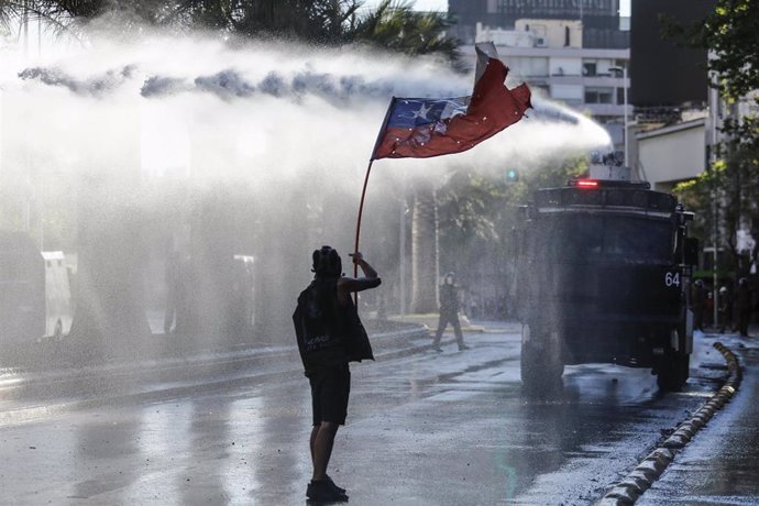 Archivo - Imagen de archivo de un manifestante frente a un carro lanza aguas de Carabineros en el marco del estallido social chileno