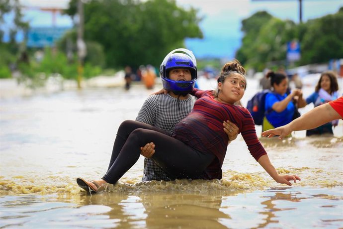 Archivo - 05 November 2020, Honduras, La Lima: A man carries a pregnant woman through a flooded road after heavy rainfall throughout the region caused by Hurricane Eta. Photo: Stringer/dpa