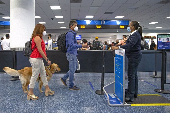 Archivo - 22 November 2020, US, Miami: Travellers with their dog walk through a security checkpoint at Miami International Airport. The Centers for Disease Control and Prevention (CDC) pleaded with Americans not to travel for Thanksgiving and not to spe