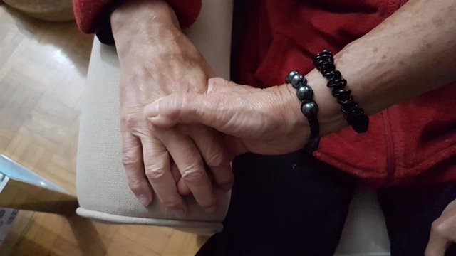 Archivo - Una mujer coge la mano de su marido con Alzheimer.