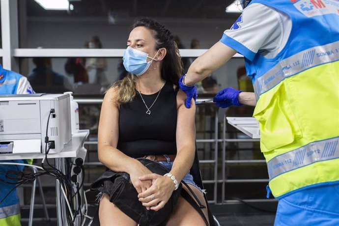 Archivo - Un sanitario administra una dosis de la vacuna de Pfizer a una mujer en el Wizink Center durante la primera noche en la que el recinto está abierto a la vacunación, a 1 de julio de 2021, en Madrid (España). El centro de vacunación masiva del W