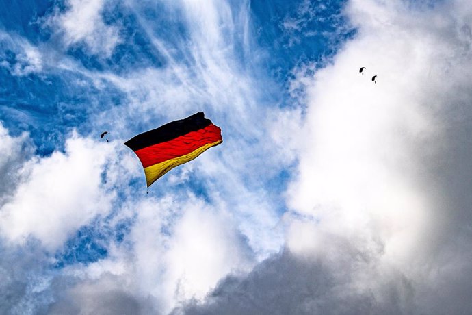 02 October 2021, North Rhine-Westphalia, Bueren: Skydivers unfurl a Germany flag in the sky above Paderborn-Lippstadt Airport. Seven skydivers want to raise a flag that is bigger than ever before during a jump to set a new world record. Photo: David Ind