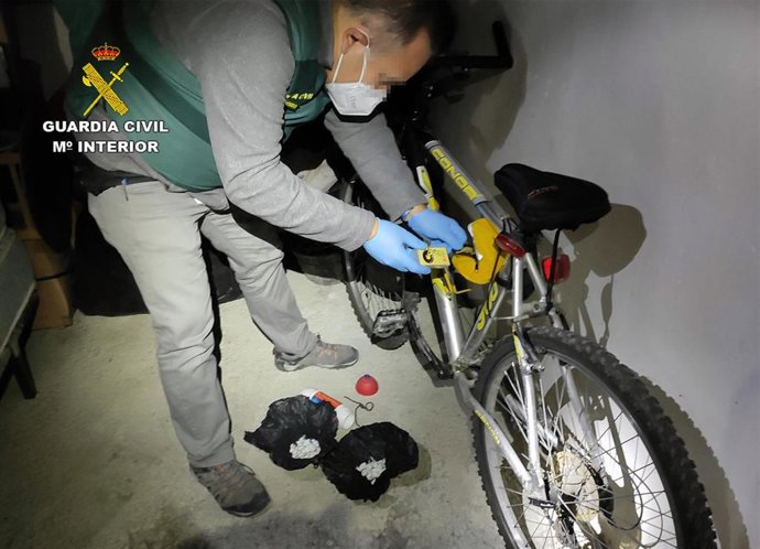 Un agente de la Guardia Civil inspecciona parte de una bicicleta durante el registro