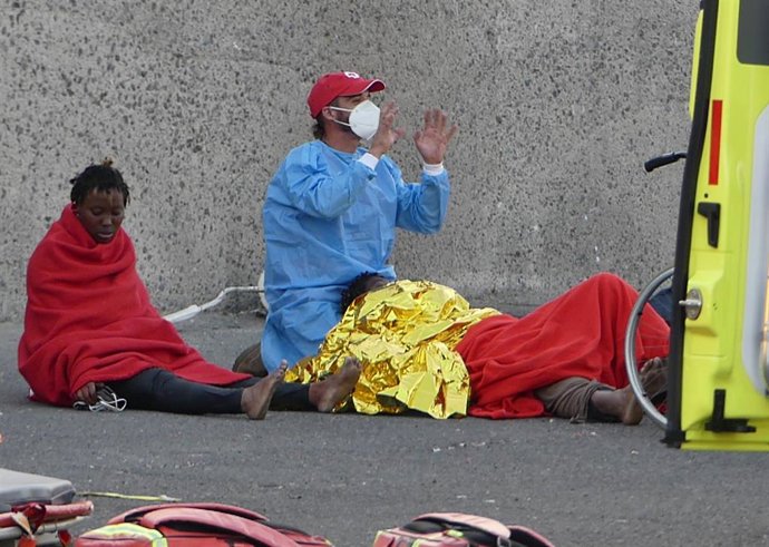 Archivo - Un sanitario da asistencia a una mujer migrante
