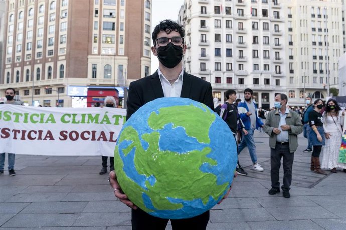 Un hombre con una bola del mundo en una concentración bajo el lema No habrá justicia climática sin justicia social en Callao, Madrid(España).