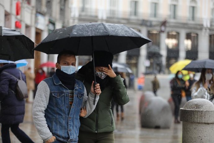 Archivo - Transeúntes pasean protegidos con paraguas por el centro de la capital, en Madrid, (España), a 27 de noviembre de 2020. El año hidrológico, que comenzó el 1 de octubre, acumula hasta el 24 de noviembre un 16 por ciento menos lluvias de lo norm