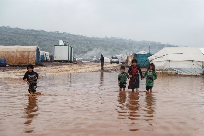 Archivo - 17 January 2021, Syria, Kafr Aruq: Syrian children wade through flood water at the flooded Tal Amin camp for internally displaced people, near the village of Kafr Aruq. The refugee camps in the north of Idlib governorate have are under threat 