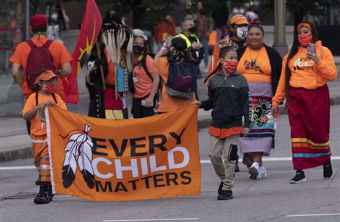 Niños indígenas llevan una bandera mientras marchan durante las ceremonias del Día Nacional de la Verdad y la Reconciliación en la Colina del Parlamento. 