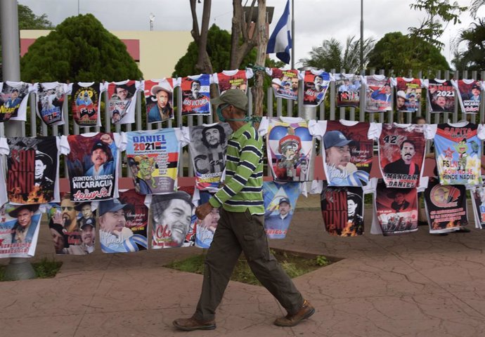 Un hombre pasea por las calles de Managua frente a un puesto de venta de camisetas con la imagen del presidente, Daniel Ortega