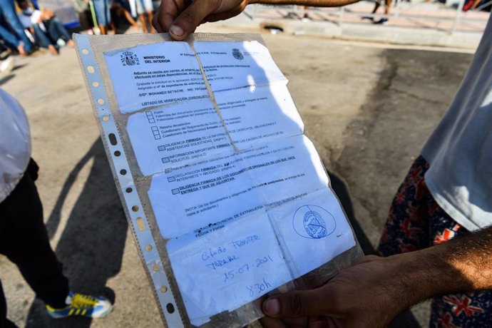 Archivo - Un joven sostiene un documento de expediente de solicitud de asilo