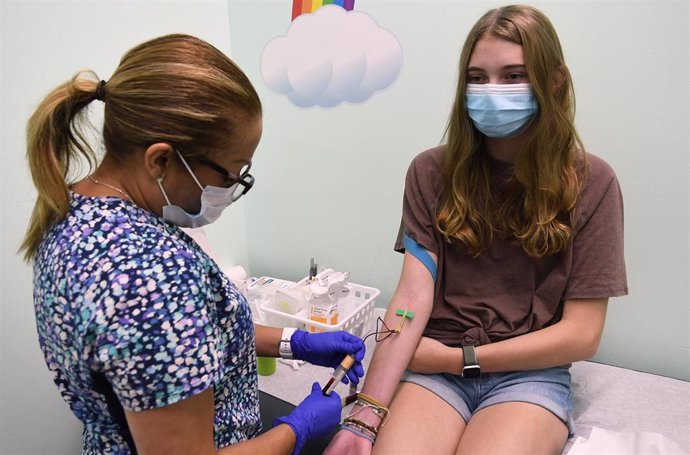 Archivo - Una trabajadora sanitaria extrae sangre de una adolescente durante una prueba sobre el uso de la vacuna de Moderna en menores