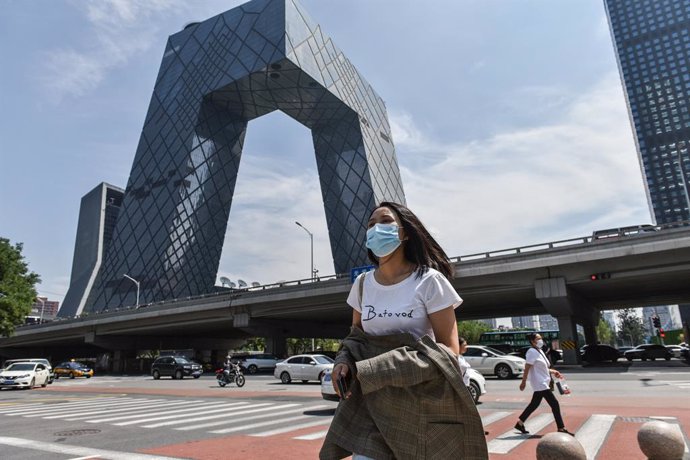 Archivo - 23 July 2021, China, Beijing: A woman walks near the China Central Television (CCTV) building at the international trade area of Beijing. China has strongly rejected plans by the World Health Organization (WHO) to take a closer look at a labor