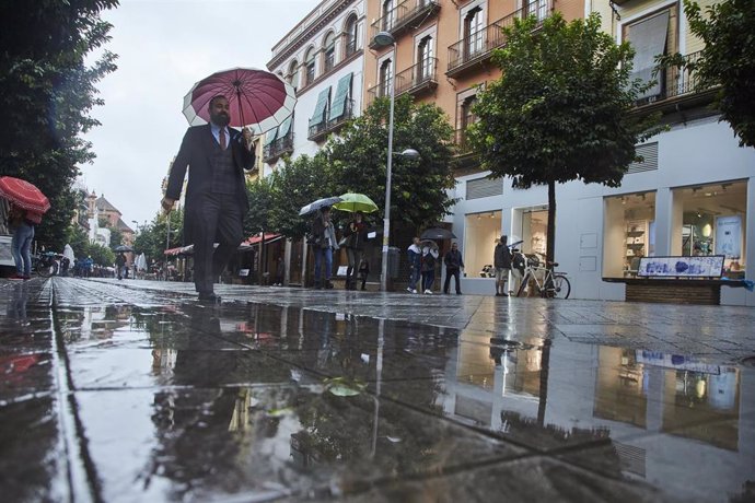 Un invitado de una boda pasea por Sevilla bajo la lluvia