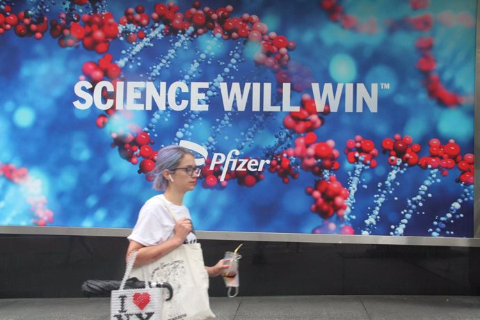 Archivo - 23 August 2021, US, New York: A woman walks in front of a poster with Pfizer company lettering. The US Food and Drug Administration (FDA) has granted full approval to the drug from German manufacturer BioNTech and its US partner Pfizer as the 