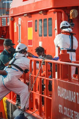 Archivo - Trabajadores ayudan a una mujer a salir de la embarcación 'Guardamar Talía tras el rescate de una patera en aguas canarias