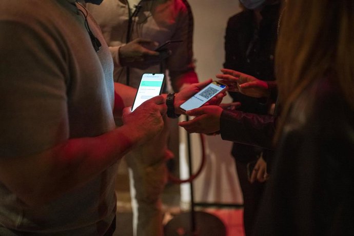 Una persona muestra un código QR para entrar a una discoteca.