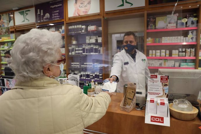 Archivo - Una anciana recoge una mascarilla FFP2 en la farmacia situada en la C/Tucán (Carabanchel), en Madrid (España), a 4 de febrero de 2021.