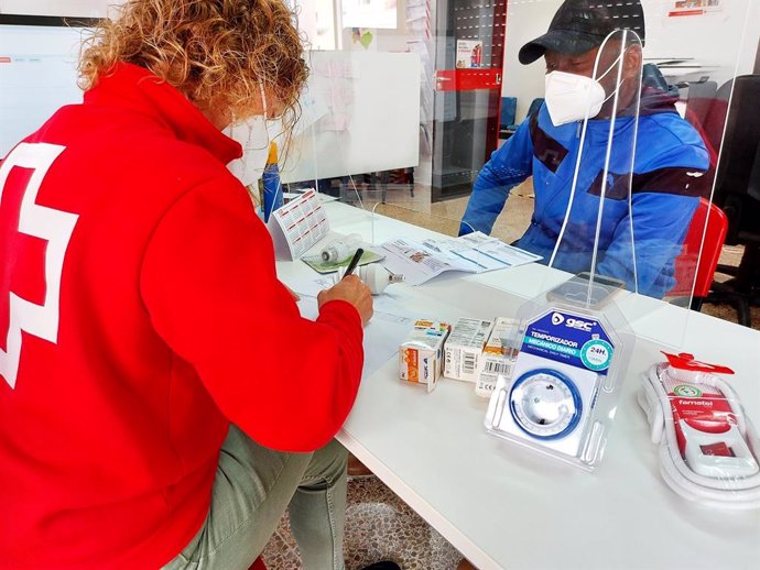 Archivo - Una voluntaria de Cruz Roja ofrece información para ahorrar en la factura de la luz a familias vulnerables.