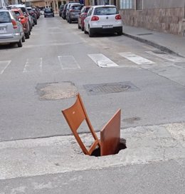 Una silla en una agujero en la calzada en El Arenal.
