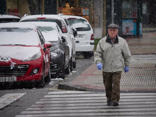 Archivo - Un hombre protegido con guantes camina bajo la nieve, en Pamplona (Navarra, España) 
