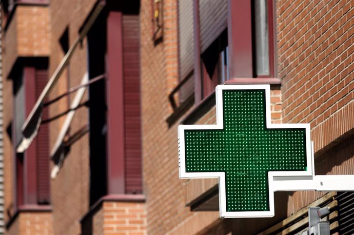 Archivo - Una señal luminosa de la cruz verde a la entrada de una farmacia.