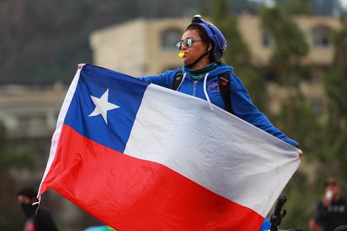 Archivo - Una mujer sostiene una bandera de Chile. 