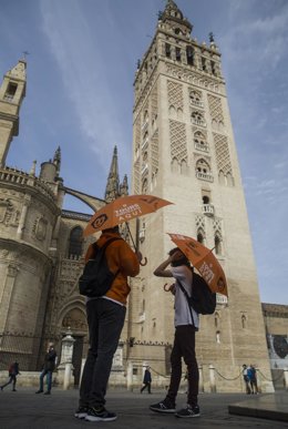 Archivo - Guías turísticos esperan la llegada de clientes junto a la Giralda