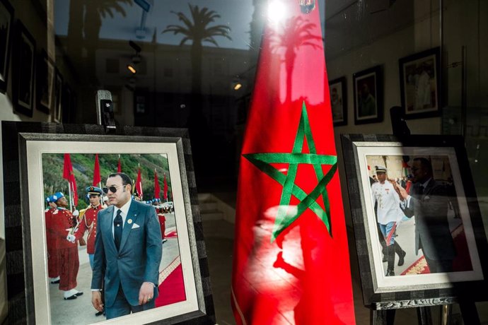 Archivo - Una bandera de Marruecos y una fotografía del rey Mohamed VI en un escaparate en Rabat.