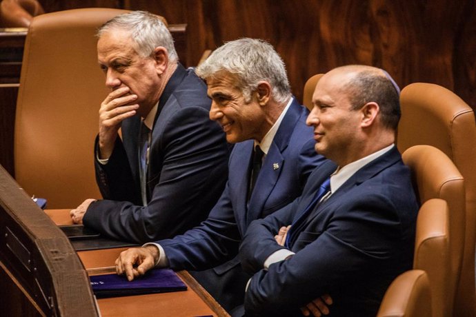 Archivo - 13 June 2021, Israel, Jerusalem: New Israeli Prime Ministers Naftali Bennett (R), leader of the Yamina right-wing alliance, speaks with Yair Lapid (C) leader of the Yesh Atid opposition centrist party, at a session of the Israeli Parliament (K