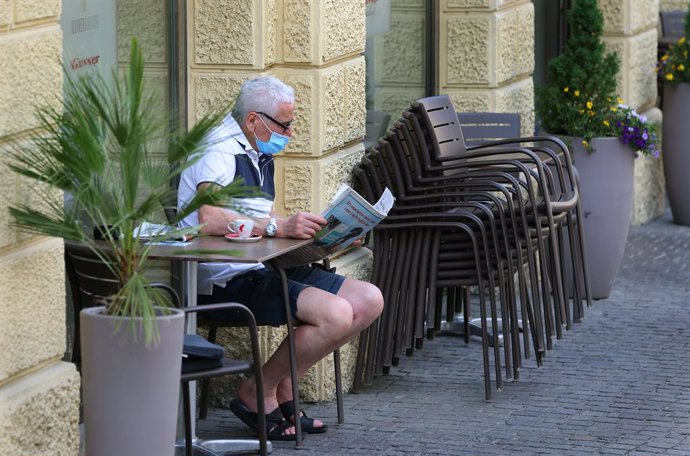 Archivo - Un hombre con mascarilla lee un periódico durante la pandemia de coronavirus en Italia