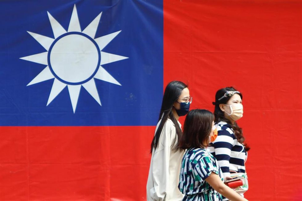 Tres personas pasean frente a una bandera de Taiwán