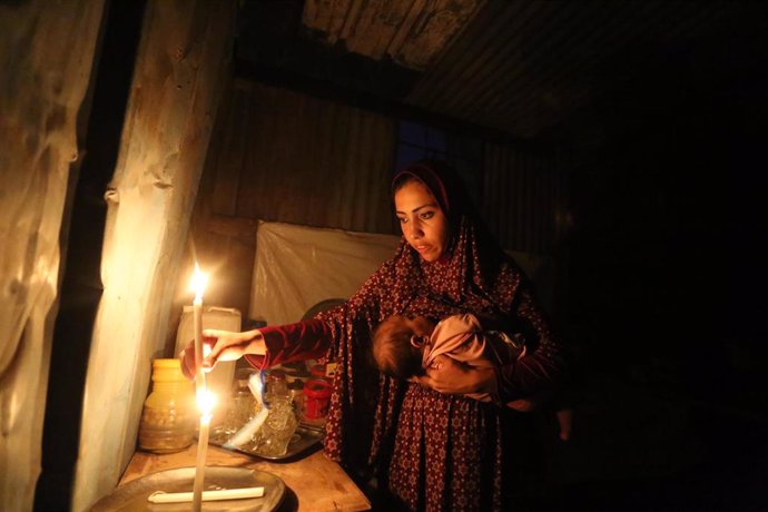 Mujer con un bebé iluminada por las velas en la Franja de Gaza