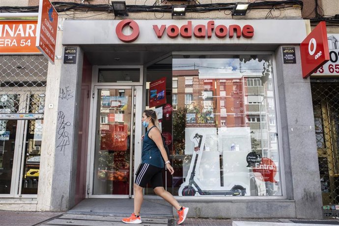 Archivo - Una persona pasa delante de una tienda de Vodafone en Madrid.
