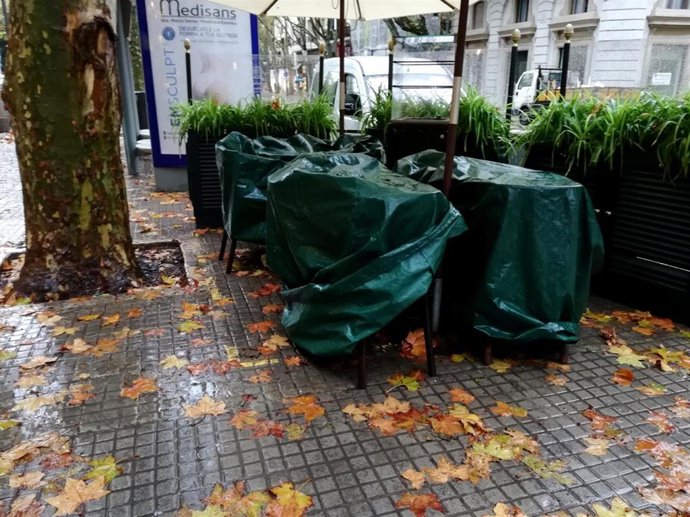 Archivo - Mesas y sillas de terrazas cubiertas por una lona un día de lluvia en Palma.