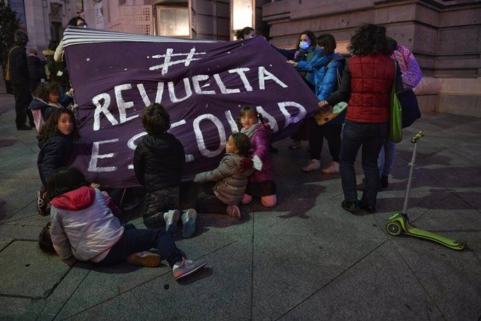 Varios niños y sus padres sujetan una pancarta de 'Revuelta Escolar', durante una concentración en recuerdo a la niña de seis años fallecida tras ser atropellada a la salida de su colegio en el barrio de Mirasierra, en la plaza de Cibeles, a 5 de noviem