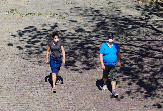 Archivo - Dos ciudadanos pasean con mascarilla. 